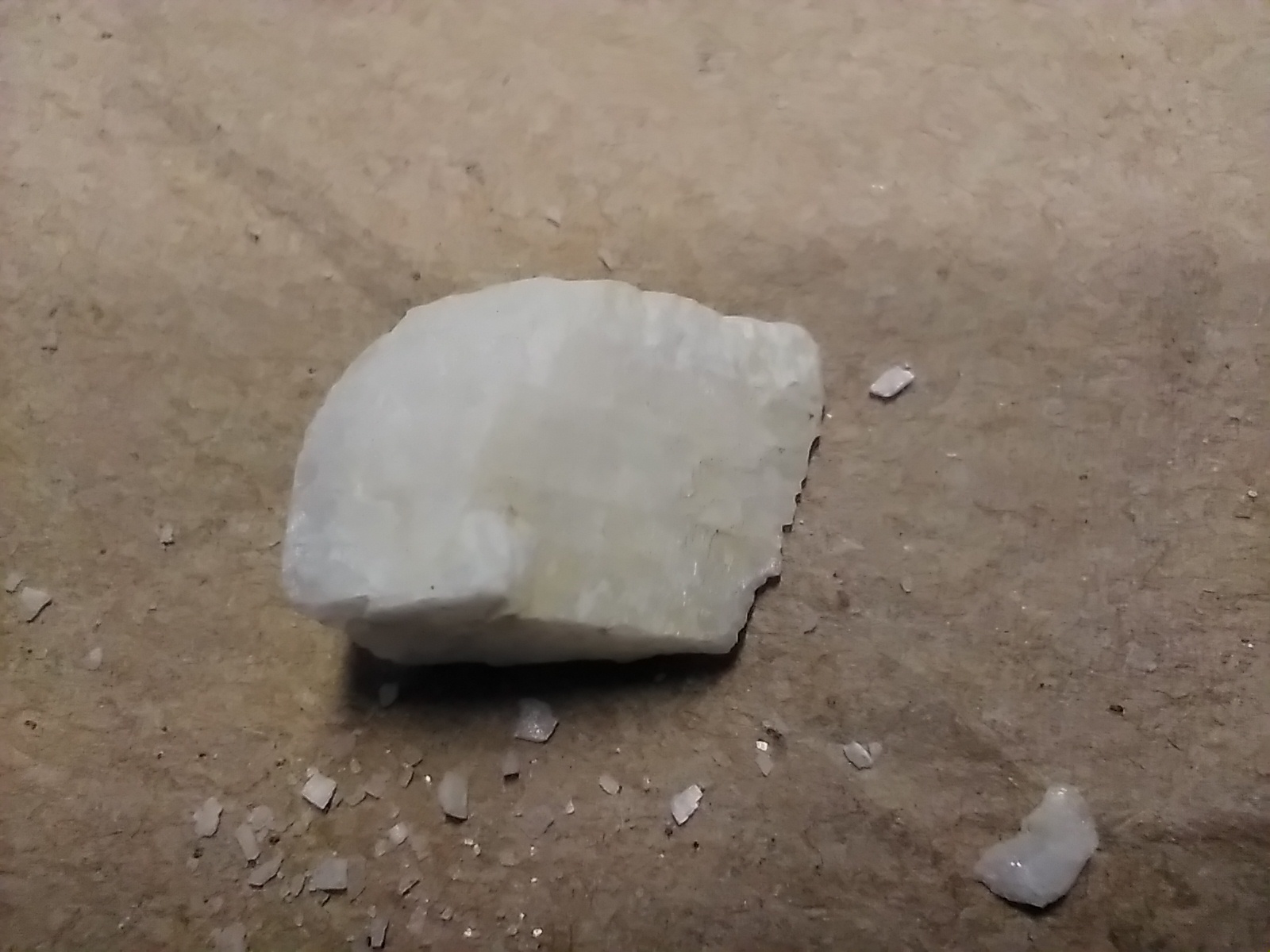 A single white barite lump on a beige surface